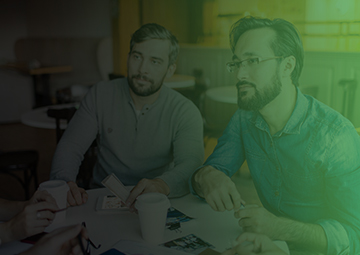 Three men engaged in discussion at a table, set against a vibrant green background, symbolizing collaboration in digital marketing.